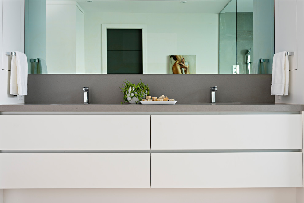 Exempel på ett mycket stort modernt grå grått en-suite badrum, med släta luckor, vita skåp, en kantlös dusch, en vägghängd toalettstol, grå kakel, porslinskakel, vita väggar, ljust trägolv, ett undermonterad handfat, bänkskiva i kvarts och med dusch som är öppen