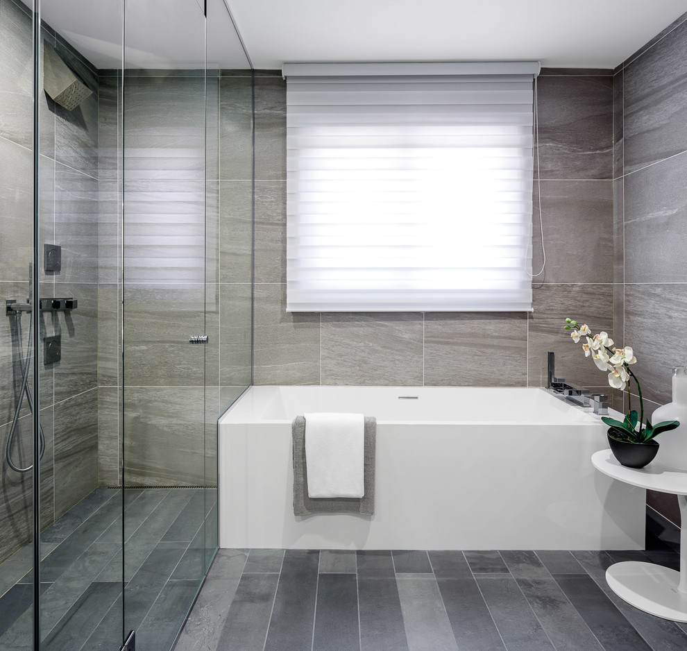Cette photo montre une grande salle de bain principale tendance avec un placard à porte plane, des portes de placard grises, une baignoire d'angle, une douche d'angle, WC séparés, un carrelage gris, un mur gris et un lavabo posé.