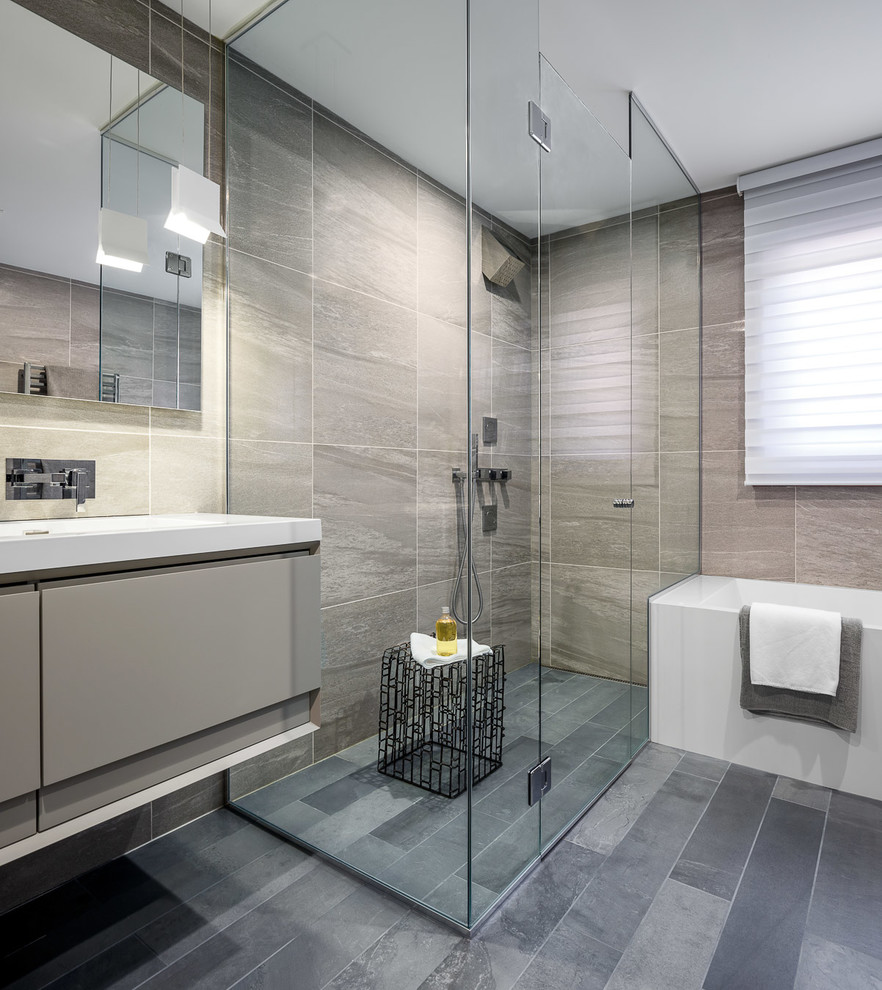 Großes Modernes Badezimmer En Suite mit flächenbündigen Schrankfronten, grauen Schränken, Eckbadewanne, Eckdusche, Wandtoilette mit Spülkasten, grauen Fliesen, grauer Wandfarbe und Einbauwaschbecken in Toronto