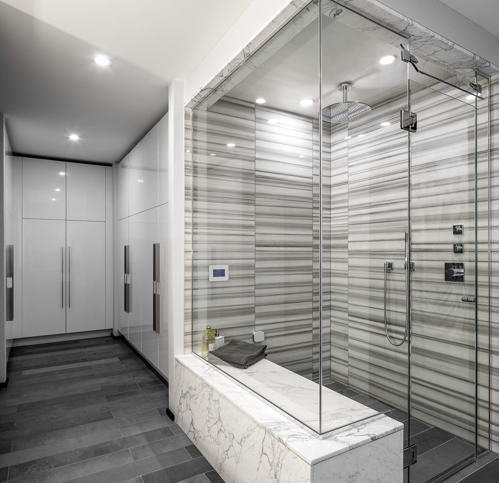 This is an example of a large contemporary ensuite bathroom in Ottawa with flat-panel cabinets, grey cabinets, a corner bath, a walk-in shower, a two-piece toilet, grey tiles, grey walls and a built-in sink.