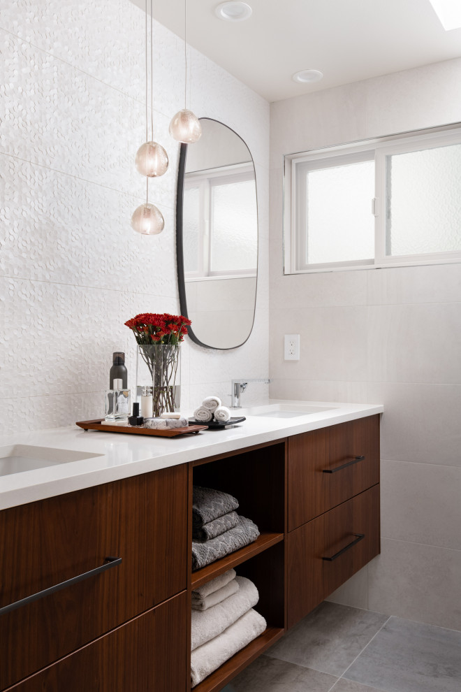 Modern inredning av ett litet vit vitt en-suite badrum, med släta luckor, skåp i mellenmörkt trä, vit kakel, porslinskakel, klinkergolv i porslin, ett undermonterad handfat, bänkskiva i kvarts och grått golv