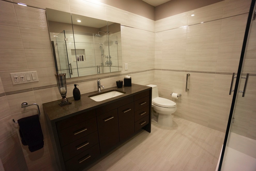 Modern inredning av ett mellanstort badrum, med ett undermonterad handfat, släta luckor, skåp i mörkt trä, bänkskiva i kvarts, en hörndusch, en toalettstol med hel cisternkåpa, grå kakel, porslinskakel, grå väggar och klinkergolv i keramik