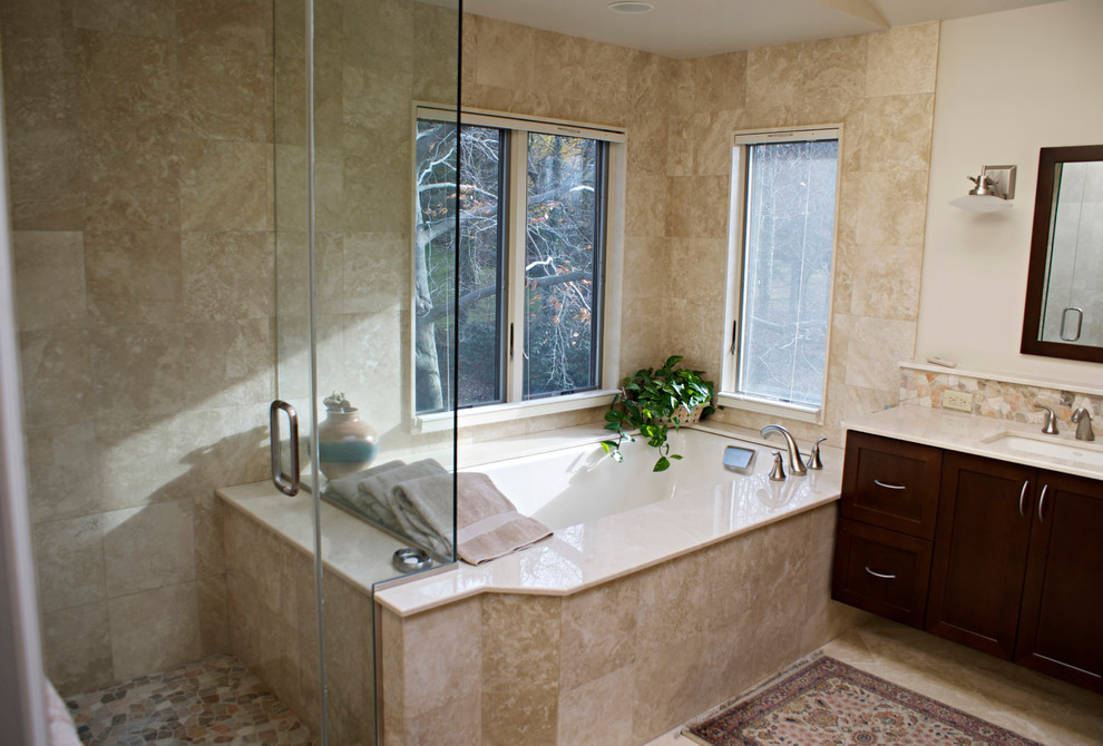 Идея дизайна: главная ванная комната в классическом стиле с врезной раковиной, фасадами в стиле шейкер, темными деревянными фасадами, мраморной столешницей, полновстраиваемой ванной, угловым душем, бежевой плиткой, каменной плиткой, белыми стенами и мраморным полом