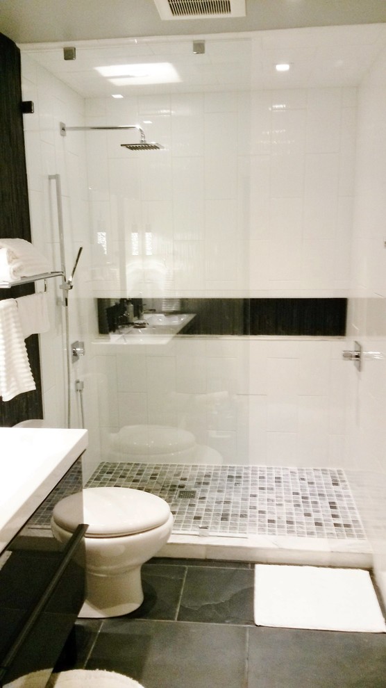 Foto de cuarto de baño principal minimalista de tamaño medio con armarios con paneles lisos, puertas de armario negras, ducha empotrada, sanitario de una pieza, paredes grises, lavabo integrado y encimera de acrílico
