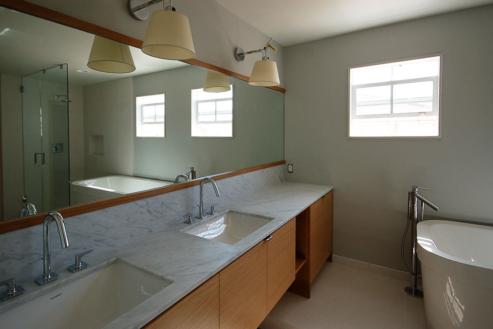 Inredning av ett modernt mellanstort en-suite badrum, med ett undermonterad handfat, släta luckor, skåp i mörkt trä, marmorbänkskiva, ett fristående badkar och klinkergolv i porslin