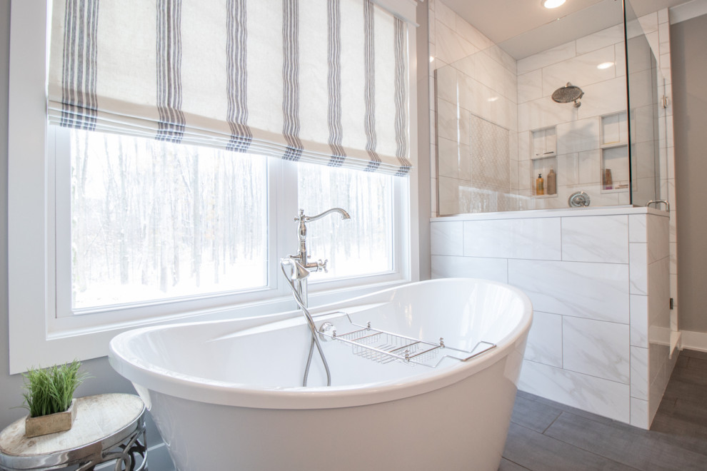 Cette image montre une salle de bain principale design avec une baignoire indépendante, une douche d'angle, un carrelage blanc, du carrelage en marbre, un mur gris et une cabine de douche à porte battante.