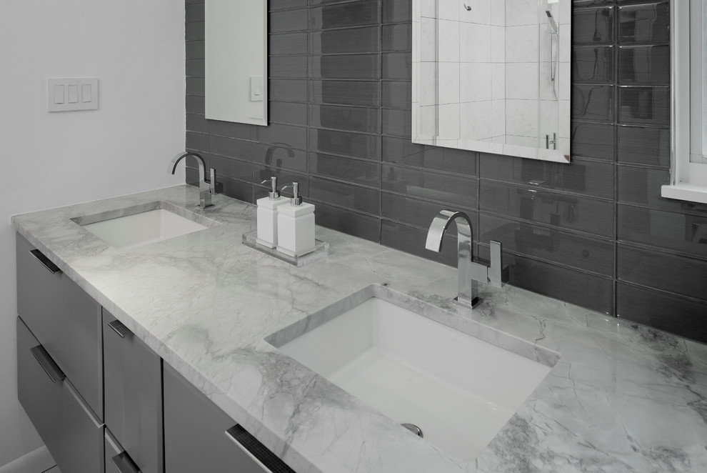 Inspiration for a medium sized modern ensuite bathroom in Baltimore with flat-panel cabinets, grey cabinets, a wall mounted toilet, grey tiles, glass tiles, white walls, porcelain flooring, a submerged sink and quartz worktops.