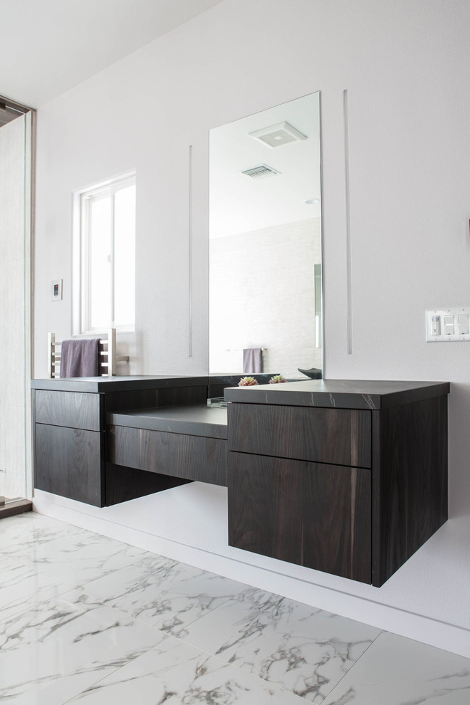 Example of a mid-sized minimalist master marble floor and white floor bathroom design in Los Angeles with flat-panel cabinets, dark wood cabinets, white walls, a vessel sink, quartz countertops, a hinged shower door and black countertops
