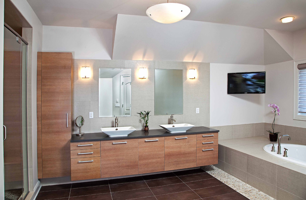 На фото: большая главная ванная комната в современном стиле с настольной раковиной, плоскими фасадами, фасадами цвета дерева среднего тона, накладной ванной, душем в нише, коричневой плиткой, галечной плиткой и серыми стенами