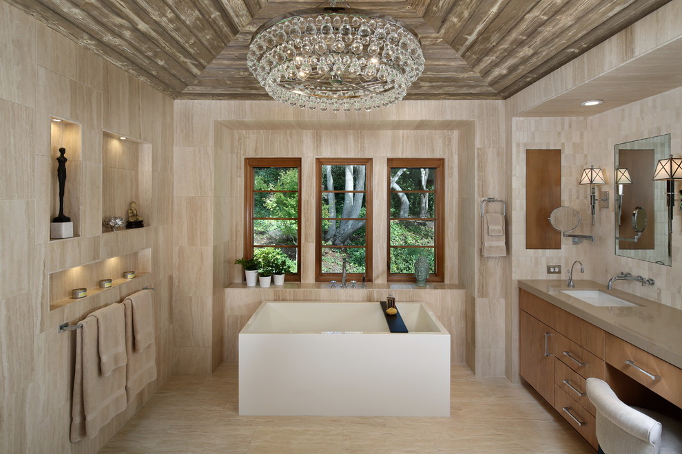 Inspiration för moderna en-suite badrum, med släta luckor, skåp i ljust trä, ett fristående badkar, beige kakel, beige väggar, ett undermonterad handfat, beiget golv, travertinkakel och travertin golv