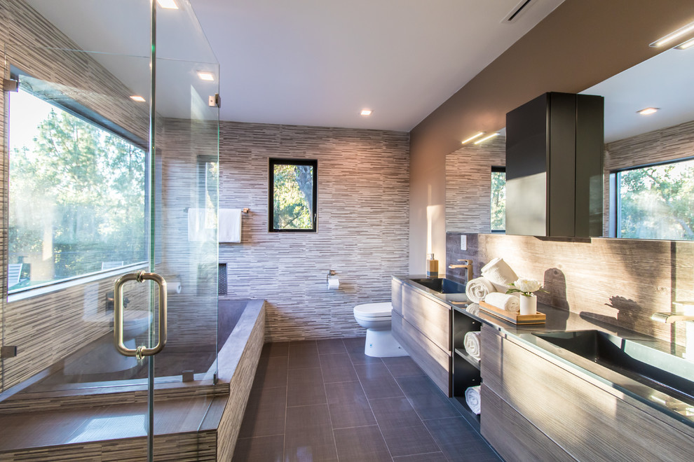 Идея дизайна: большая главная ванная комната в стиле модернизм с плоскими фасадами, коричневыми фасадами, накладной ванной, угловым душем, раздельным унитазом, разноцветной плиткой, керамической плиткой, коричневыми стенами, полом из керамогранита, накладной раковиной, столешницей из искусственного камня, коричневым полом, душем с распашными дверями и серой столешницей
