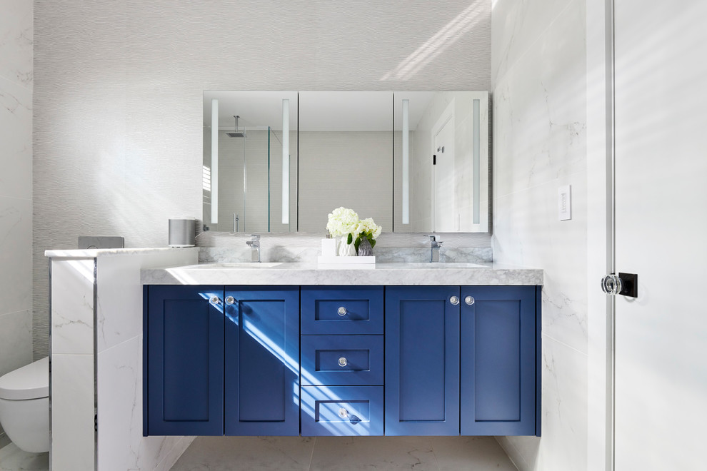 Modernes Duschbad mit Schrankfronten im Shaker-Stil, blauen Schränken, Eckdusche, Wandtoilette, grauer Wandfarbe, Unterbauwaschbecken, grauem Boden, Falttür-Duschabtrennung und grauer Waschtischplatte in New York