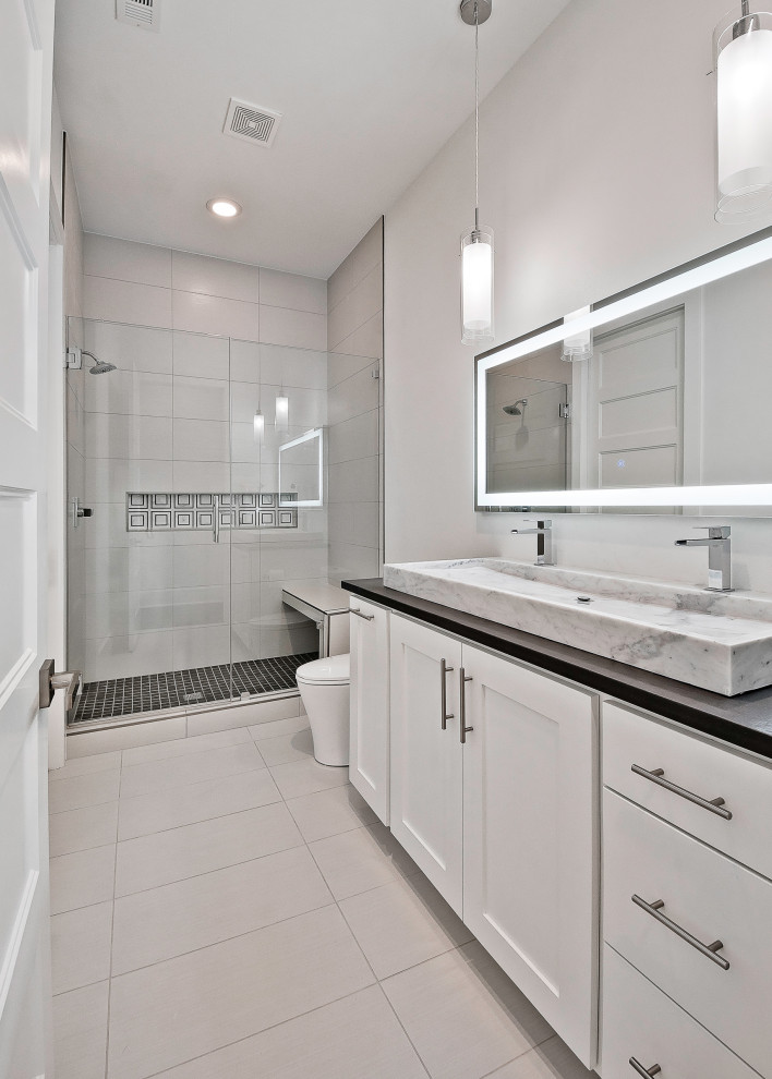Photo of a medium sized modern family bathroom in Other with recessed-panel cabinets, white cabinets, an alcove shower, a one-piece toilet, grey tiles, porcelain tiles, white walls, porcelain flooring, a submerged sink, granite worktops, grey floors, a hinged door, black worktops, a shower bench, double sinks and a built in vanity unit.