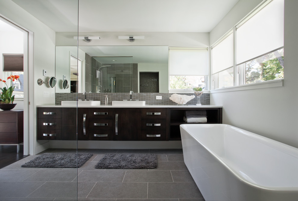 Mid-sized trendy master gray tile and glass tile ceramic tile bathroom photo in Minneapolis with a vessel sink, flat-panel cabinets, dark wood cabinets, solid surface countertops and white walls