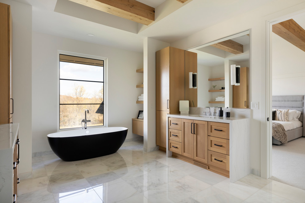 Farmhouse master marble floor, white floor, double-sink and exposed beam bathroom photo in Minneapolis with flat-panel cabinets, light wood cabinets, white walls, an undermount sink, quartz countertops, a hinged shower door, white countertops and a built-in vanity