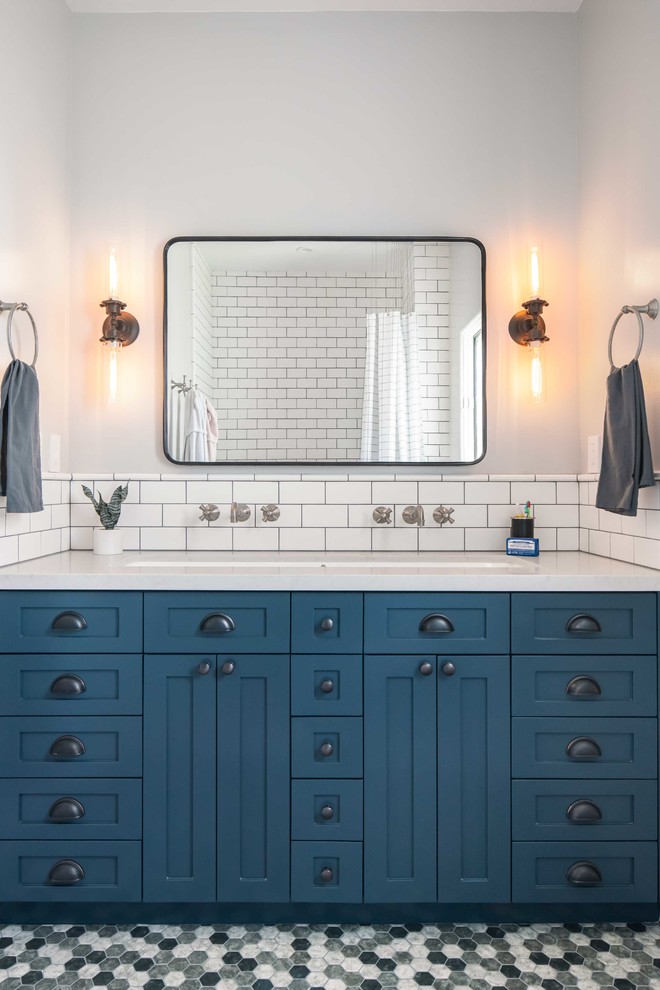 ロサンゼルスにある高級な中くらいなモダンスタイルのおしゃれなバスルーム (浴槽なし) (青いキャビネット、一体型トイレ	、白いタイル、サブウェイタイル、白い壁、アンダーカウンター洗面器、白い洗面カウンター、シェーカースタイル扉のキャビネット、アルコーブ型浴槽、シャワー付き浴槽	、モザイクタイル、クオーツストーンの洗面台、マルチカラーの床、シャワーカーテン) の写真