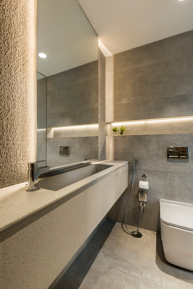 Cette photo montre une salle de bain tendance avec WC à poser, un carrelage gris, un lavabo intégré, un sol gris et un plan de toilette gris.