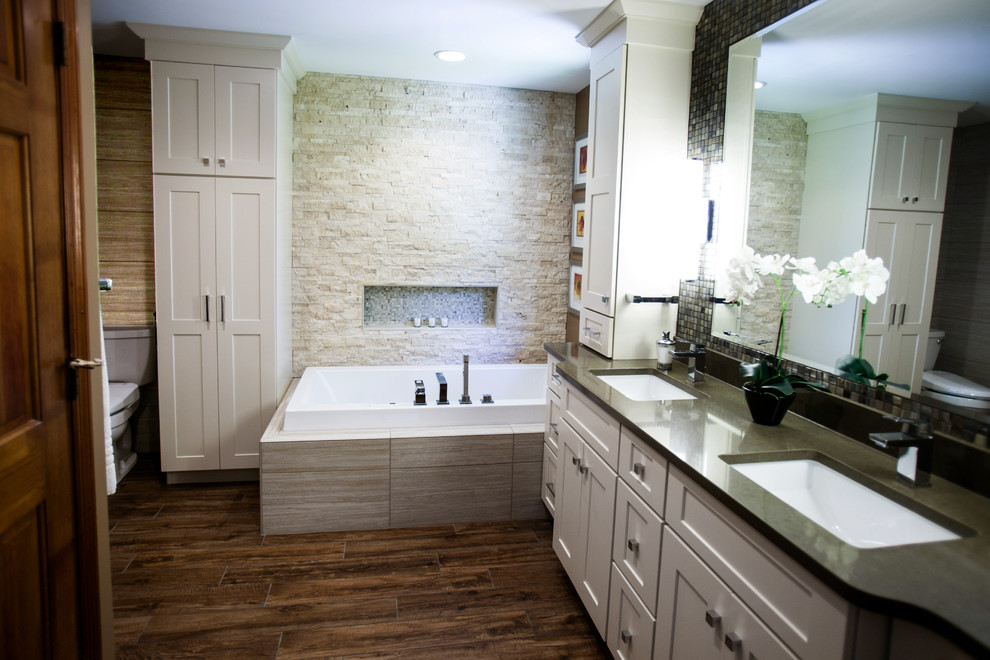 Exemple d'une très grande salle de bain principale éclectique avec un placard à porte shaker, des portes de placard blanches, un plan de toilette en quartz, une baignoire d'angle, une douche ouverte, un carrelage gris, un carrelage de pierre et un sol en carrelage de porcelaine.