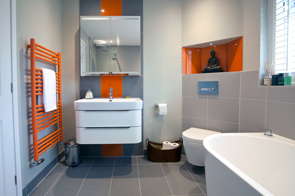 This is an example of a medium sized contemporary family bathroom in Sussex with freestanding cabinets, grey cabinets, a freestanding bath, a walk-in shower, a one-piece toilet, grey walls, ceramic flooring, an integrated sink, grey floors and an open shower.