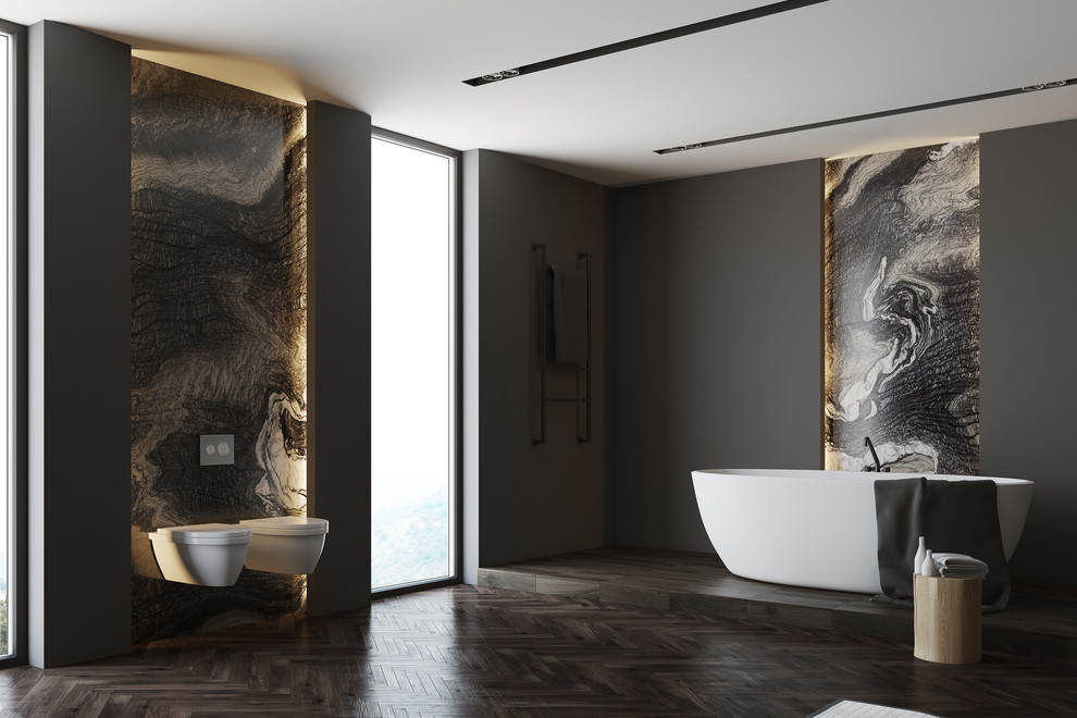 Foto på ett mellanstort funkis en-suite badrum, med ett fristående badkar, en vägghängd toalettstol, grå kakel, marmorkakel, grå väggar, mörkt trägolv och flerfärgat golv