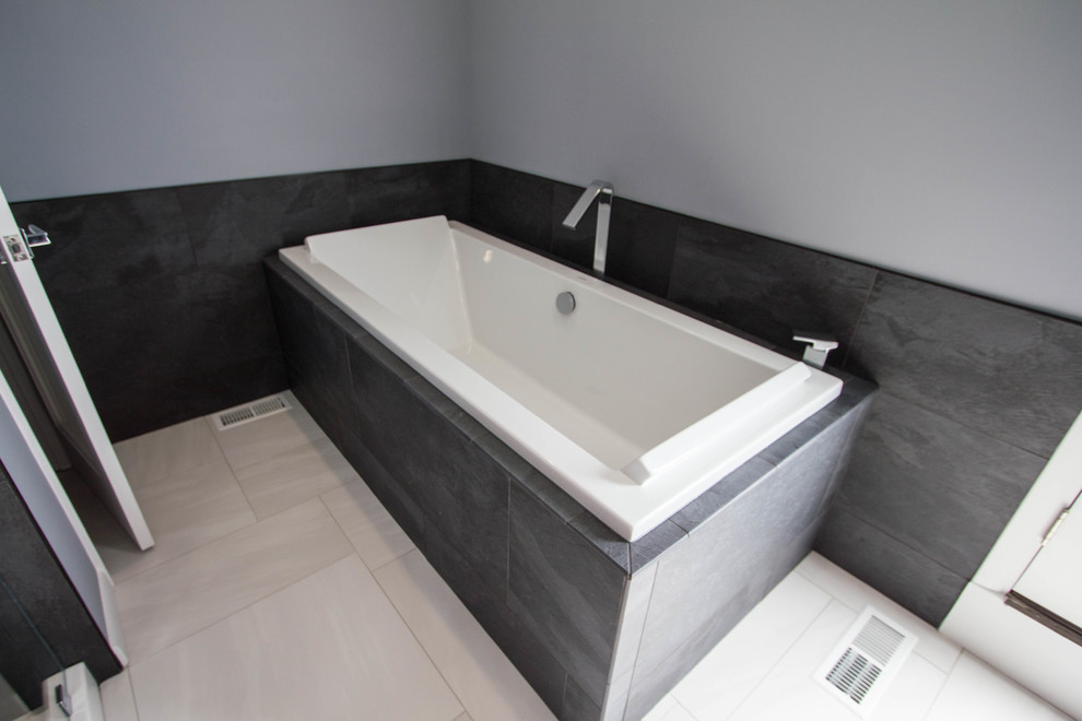 Diseño de cuarto de baño principal moderno de tamaño medio con paredes grises, suelo de baldosas de porcelana, suelo blanco, bañera encastrada, baldosas y/o azulejos negros y baldosas y/o azulejos de porcelana