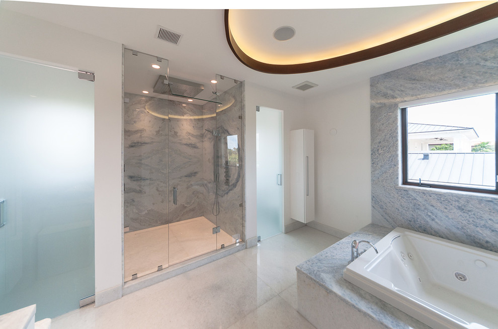 Bild på ett funkis badrum, med ett väggmonterat handfat, släta luckor, vita skåp, en jacuzzi, en öppen dusch, vit kakel och stenkakel