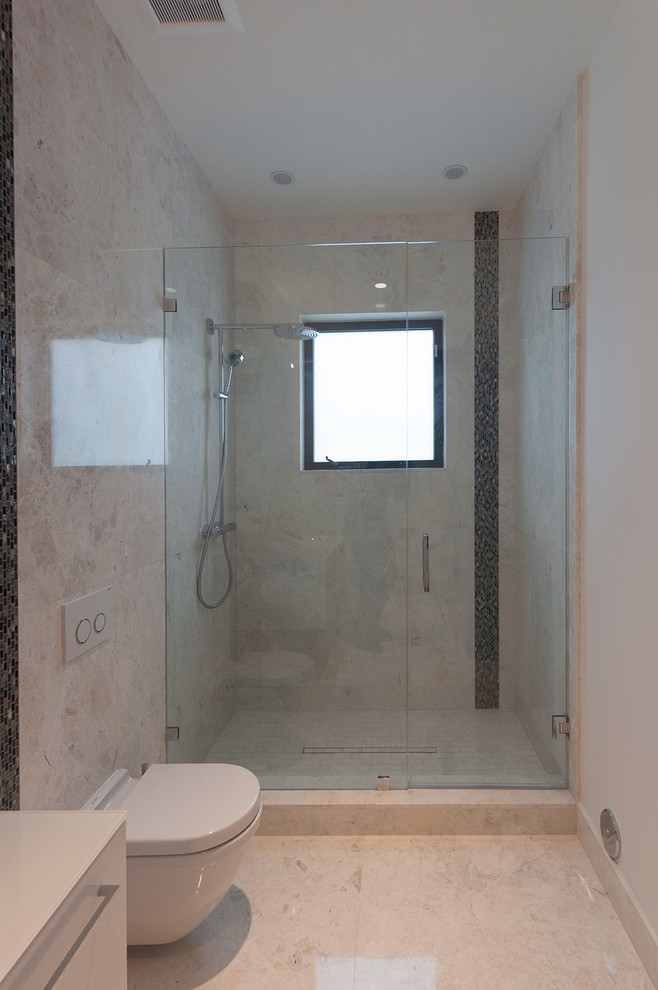 Immagine di una stanza da bagno design con doccia aperta, WC sospeso, piastrelle beige e piastrelle in pietra