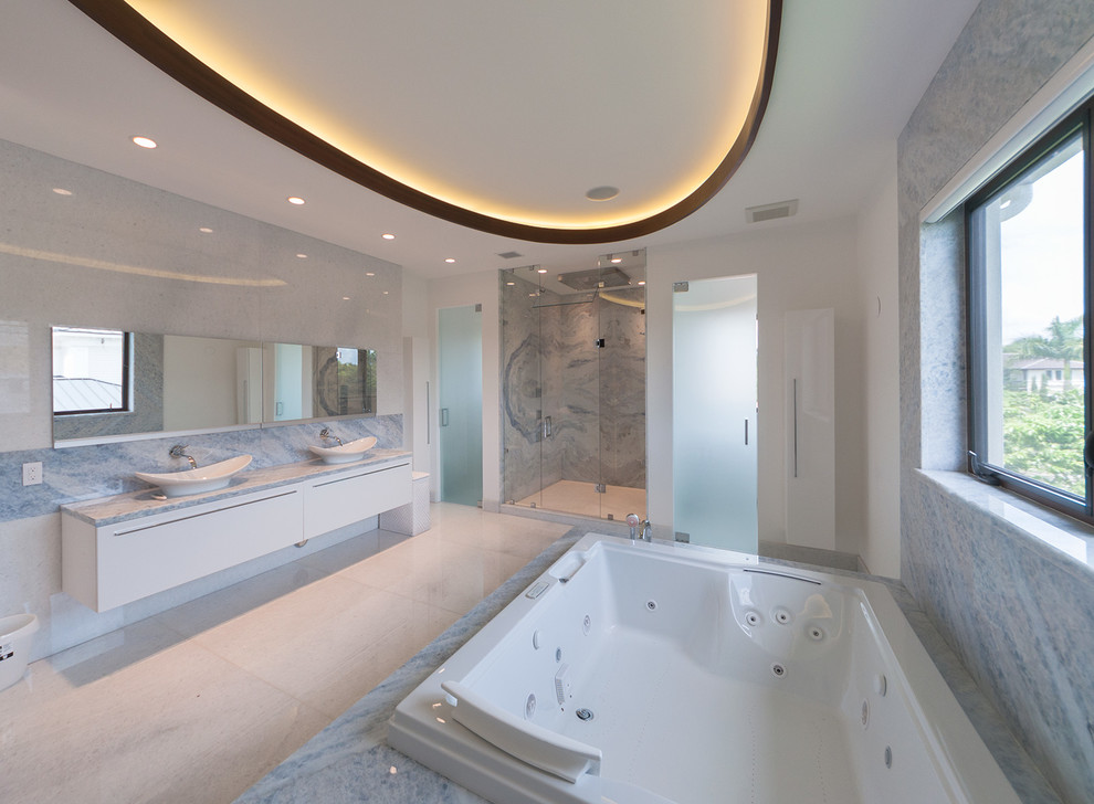 Aménagement d'une salle de bain contemporaine avec un lavabo suspendu, un placard à porte plane, des portes de placard blanches, un bain bouillonnant, une douche ouverte, un carrelage blanc et un carrelage de pierre.