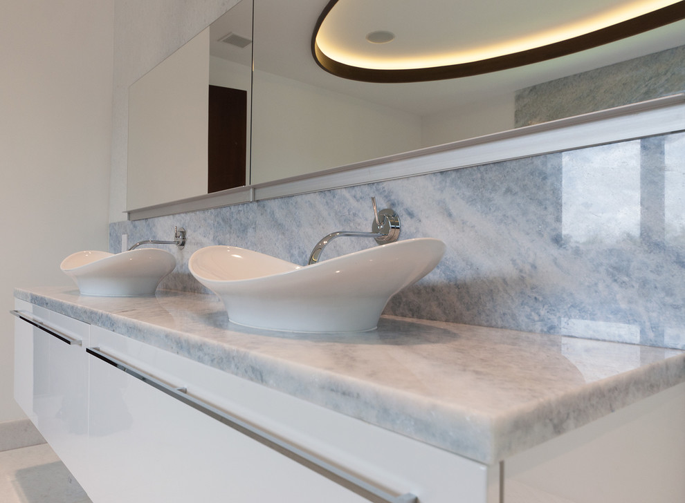 This is an example of a contemporary bathroom in Miami with a wall-mounted sink, flat-panel cabinets, white cabinets, a hot tub, white tiles and stone tiles.