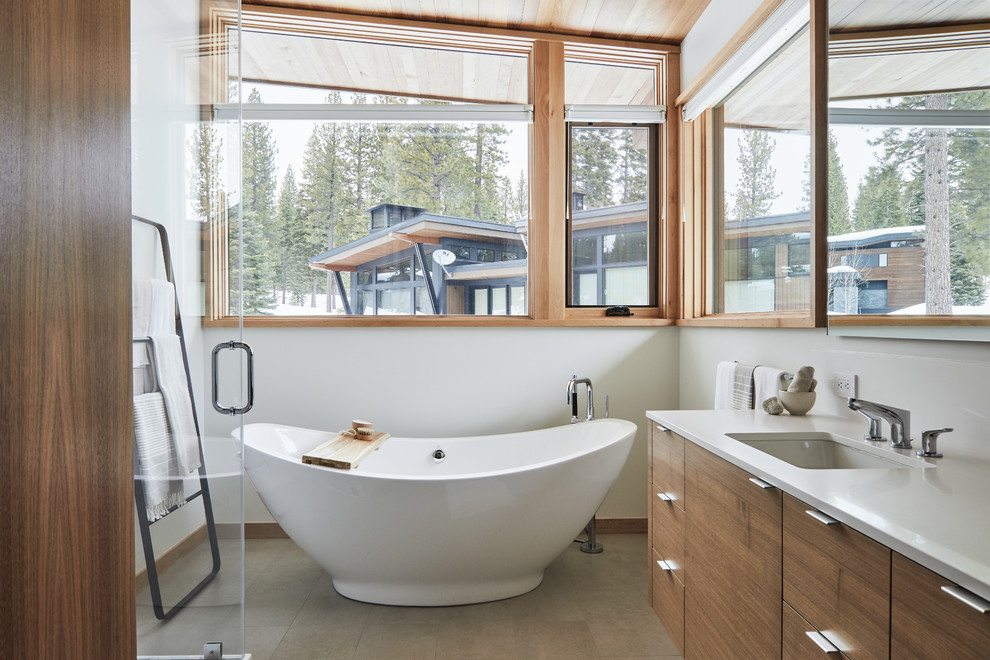 Источник вдохновения для домашнего уюта: ванная комната в современном стиле с плоскими фасадами, темными деревянными фасадами, отдельно стоящей ванной, белыми стенами, врезной раковиной, серым полом и белой столешницей