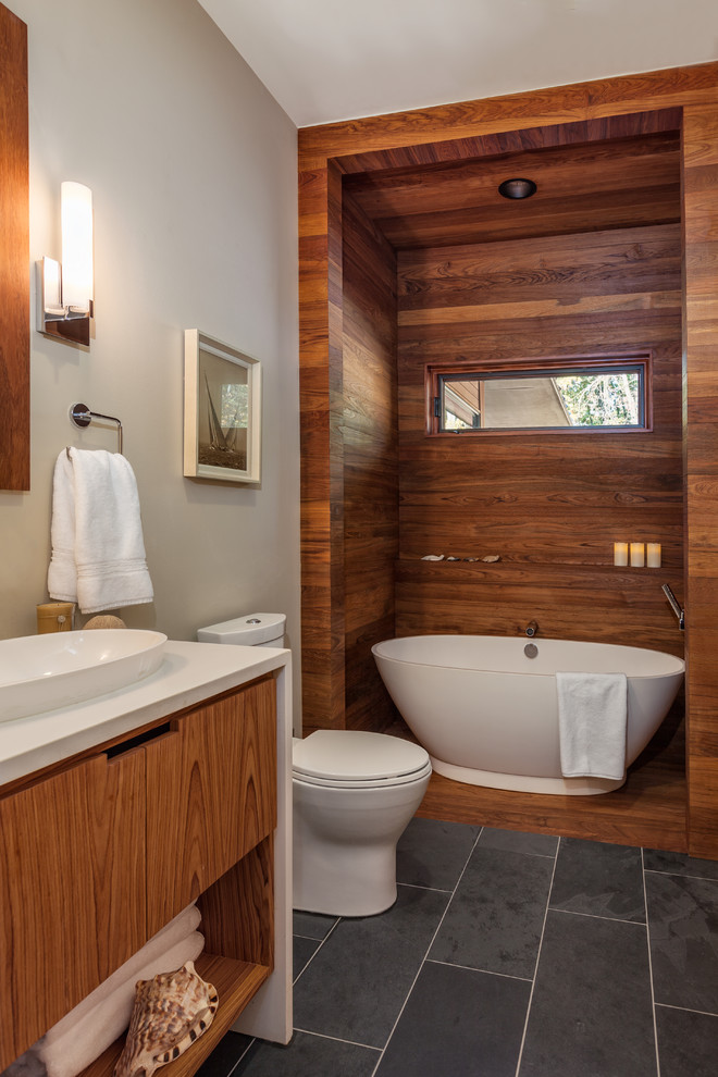 Idéer för mellanstora funkis badrum, med släta luckor, skåp i mellenmörkt trä, ett fristående badkar, en toalettstol med separat cisternkåpa, beige väggar, klinkergolv i porslin, ett fristående handfat, bänkskiva i kvarts och grått golv