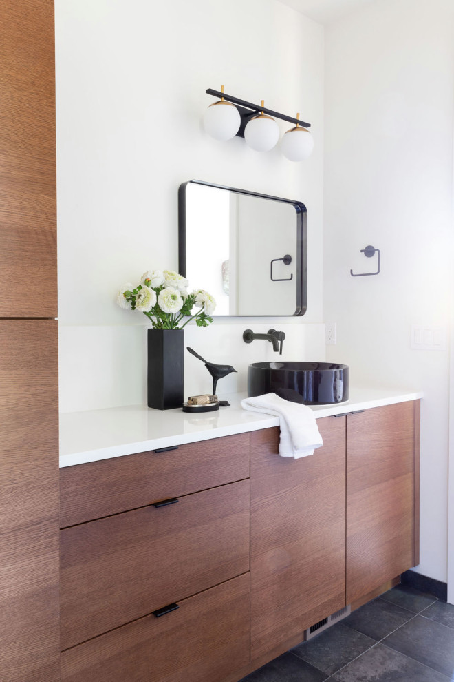 Diseño de cuarto de baño único contemporáneo con armarios con paneles lisos, puertas de armario de madera oscura, paredes blancas, lavabo sobreencimera, suelo negro y encimeras blancas