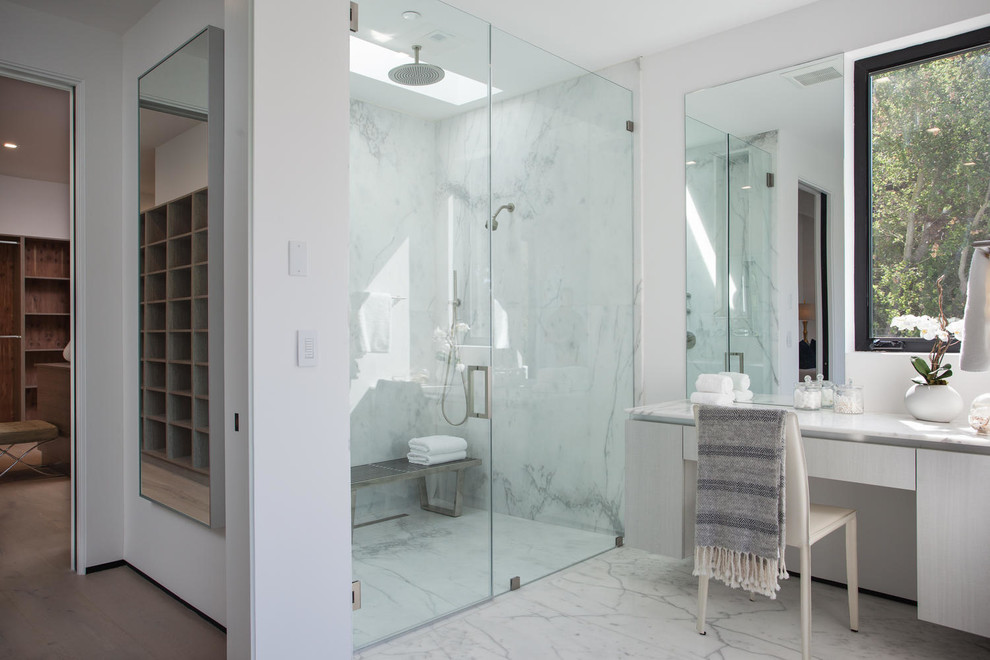 Réalisation d'une grande salle de bain principale minimaliste en bois clair avec un placard à porte plane, une baignoire indépendante, une douche à l'italienne, WC suspendus, des dalles de pierre, un mur blanc, un sol en marbre, un lavabo encastré, un plan de toilette en marbre et un carrelage blanc.
