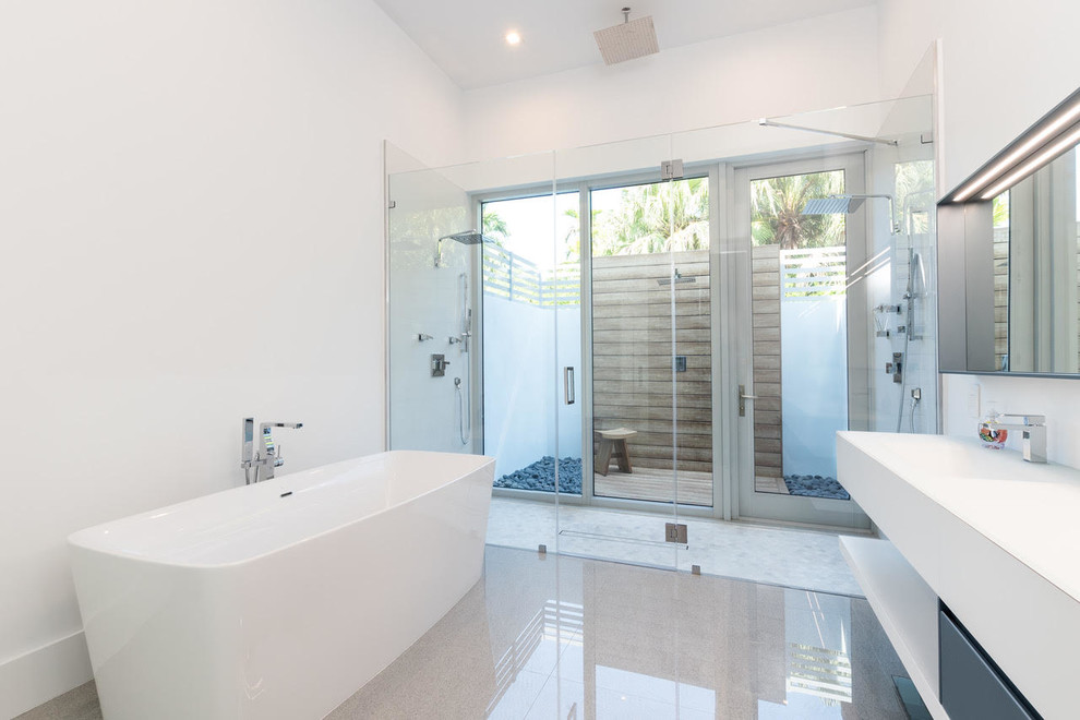 Идея дизайна: большая главная ванная комната в стиле модернизм с отдельно стоящей ванной, двойным душем, белыми стенами, бетонным полом, монолитной раковиной, столешницей из искусственного камня, серым полом, душем с распашными дверями и белой столешницей