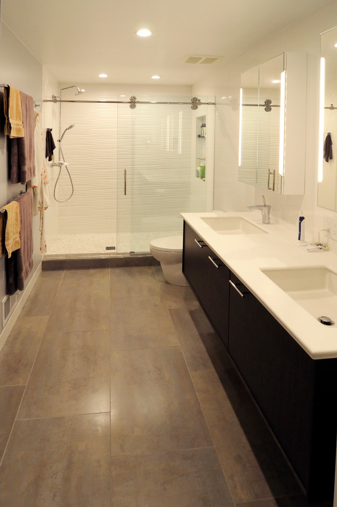 Пример оригинального дизайна: главная ванная комната среднего размера в современном стиле с монолитной раковиной, плоскими фасадами, темными деревянными фасадами, столешницей из искусственного камня, двойным душем, унитазом-моноблоком, серой плиткой, керамогранитной плиткой, белыми стенами и полом из керамогранита