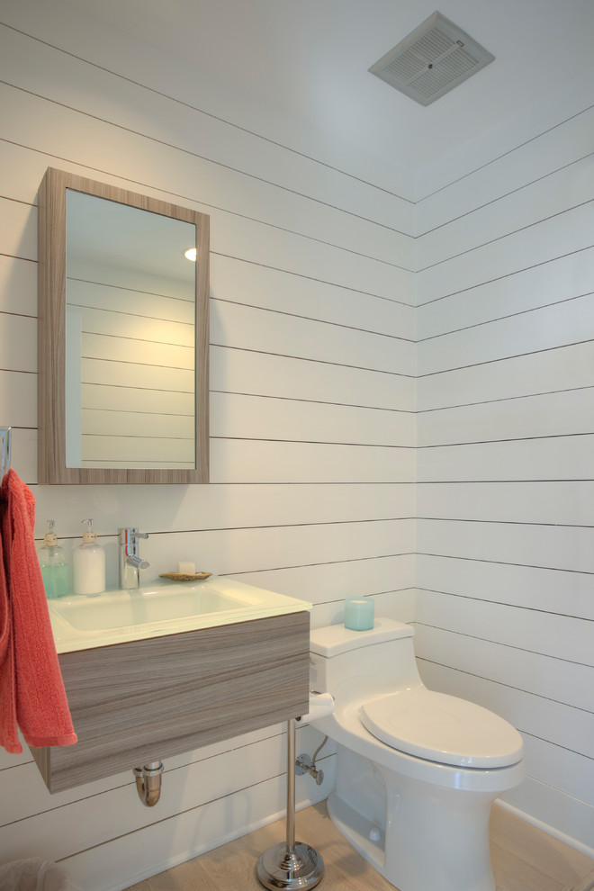 Immagine di una stanza da bagno stile marinaro di medie dimensioni con WC monopezzo, pareti bianche, parquet chiaro, lavabo sospeso e pavimento beige