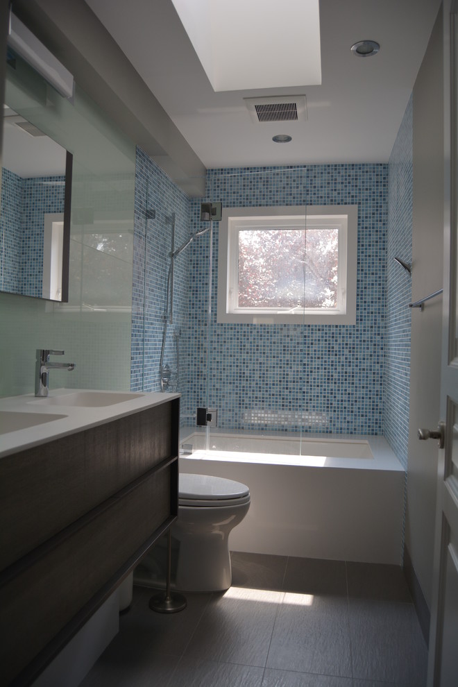 На фото: большая главная ванная комната в современном стиле с монолитной раковиной, плоскими фасадами, темными деревянными фасадами, ванной в нише, душем над ванной, раздельным унитазом, синей плиткой, плиткой мозаикой, коричневыми стенами, полом из керамогранита, столешницей из искусственного кварца, серым полом и душем с распашными дверями с