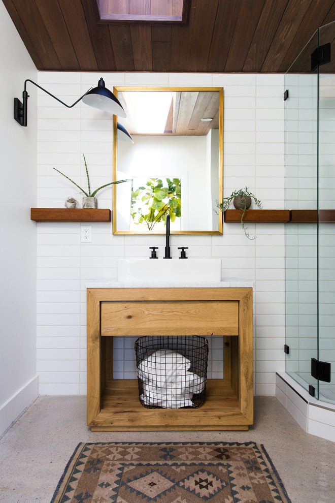 Small trendy 3/4 white tile concrete floor and gray floor corner shower photo in Salt Lake City with open cabinets, medium tone wood cabinets, white walls, a vessel sink, a hinged shower door and white countertops
