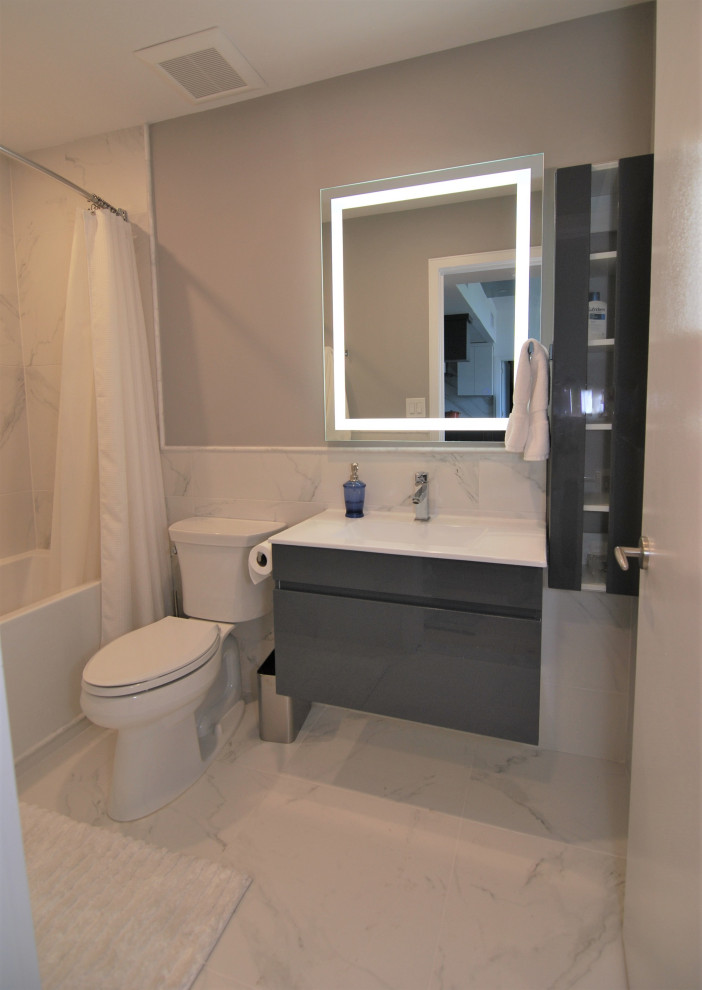 Cette photo montre une petite salle de bain moderne pour enfant avec un placard à porte plane, des portes de placard grises, une baignoire en alcôve, un combiné douche/baignoire, un carrelage blanc, des carreaux de porcelaine, un mur gris, un sol en carrelage de porcelaine, un plan vasque, un plan de toilette en surface solide, un sol blanc, une cabine de douche avec un rideau et un plan de toilette blanc.