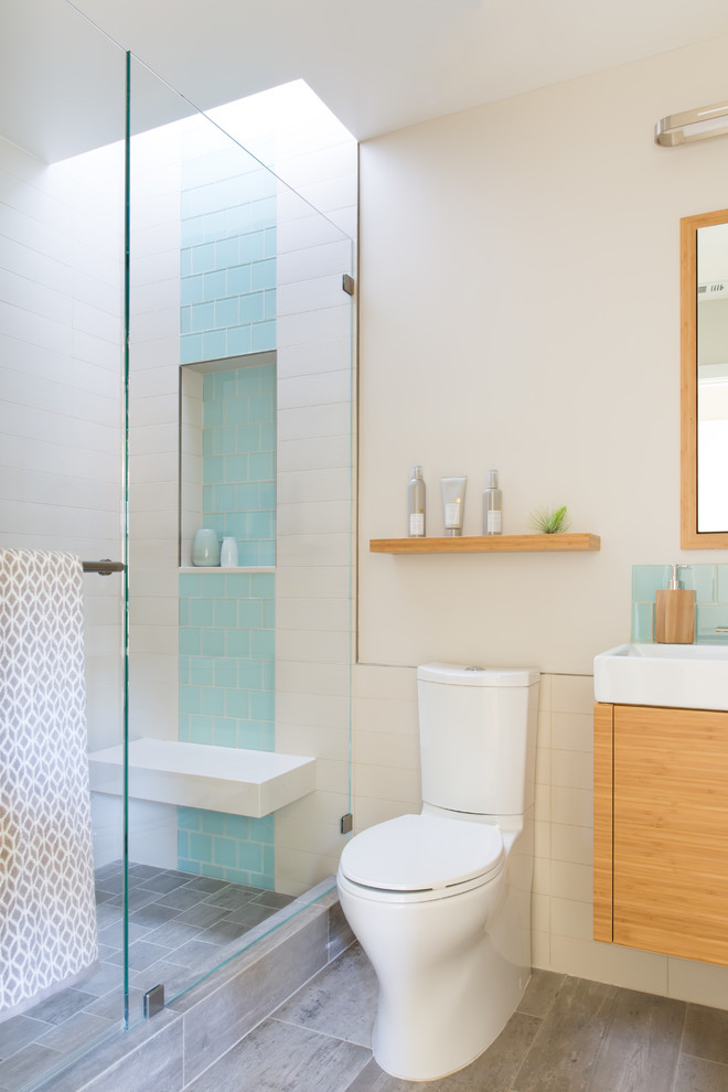 Design ideas for a small contemporary shower room bathroom in San Francisco with flat-panel cabinets, light wood cabinets, an alcove shower, a one-piece toilet, white tiles, porcelain tiles, white walls, porcelain flooring, an integrated sink, quartz worktops, grey floors and a hinged door.