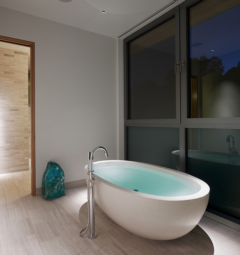 На фото: большая главная ванная комната с плоскими фасадами, светлыми деревянными фасадами, мраморной столешницей, отдельно стоящей ванной, душем в нише, белой плиткой, каменной плиткой и мраморным полом с