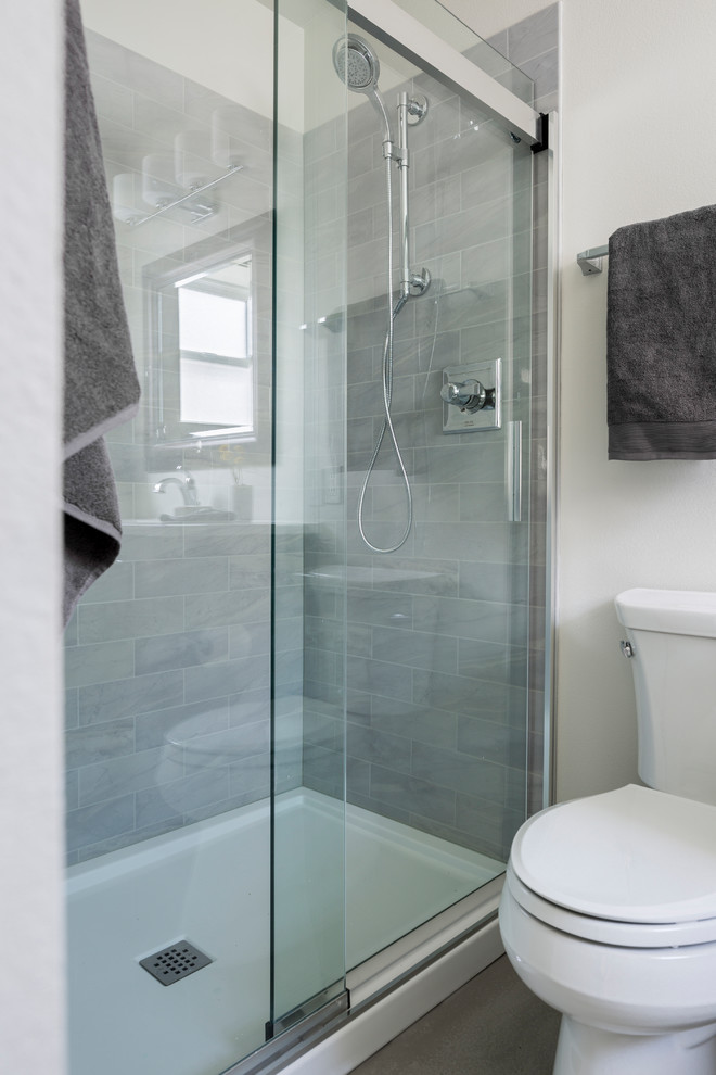 Cette image montre une petite salle de bain design avec un placard à porte plane, WC séparés, un carrelage gris, un mur blanc, sol en béton ciré, un sol gris et une cabine de douche à porte coulissante.