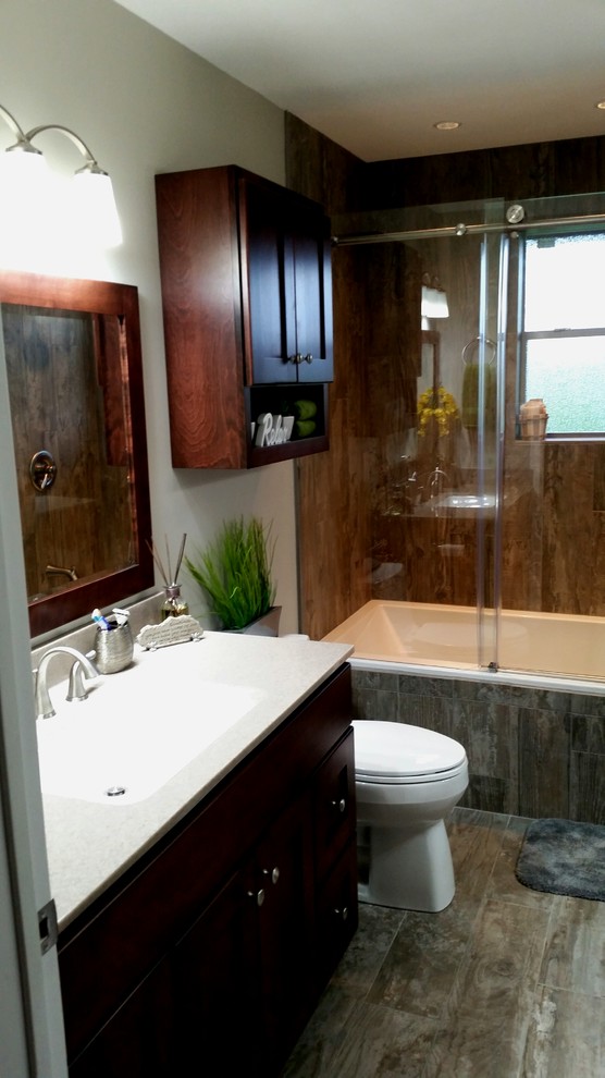 Photo of a small modern ensuite bathroom in Houston with an integrated sink, shaker cabinets, dark wood cabinets, a built-in bath, a shower/bath combination, a one-piece toilet, brown tiles, porcelain tiles, grey walls and porcelain flooring.