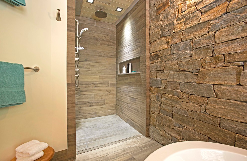 Inspiration for a large rural ensuite bathroom in Jacksonville with recessed-panel cabinets, medium wood cabinets, a freestanding bath, a built-in shower, a one-piece toilet, beige tiles, porcelain tiles, beige walls, porcelain flooring, a vessel sink, marble worktops, beige floors, an open shower and beige worktops.