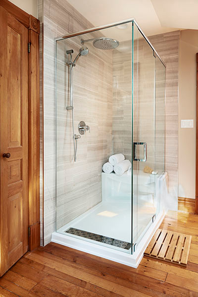 Cette photo montre une petite salle de bain principale nature avec une douche d'angle, WC à poser, un carrelage gris, des dalles de pierre, un sol en bois brun et un mur beige.