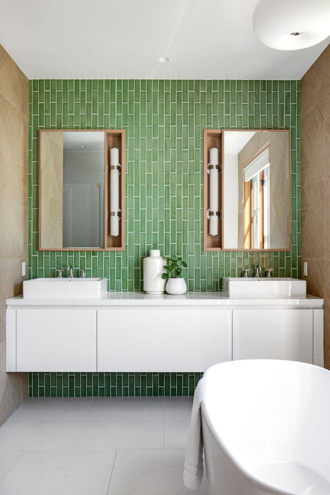 Design ideas for a medium sized contemporary ensuite bathroom in Orange County with flat-panel cabinets, white cabinets, a freestanding bath, green tiles, ceramic tiles, green walls, a vessel sink, quartz worktops, white worktops, cement flooring and grey floors.