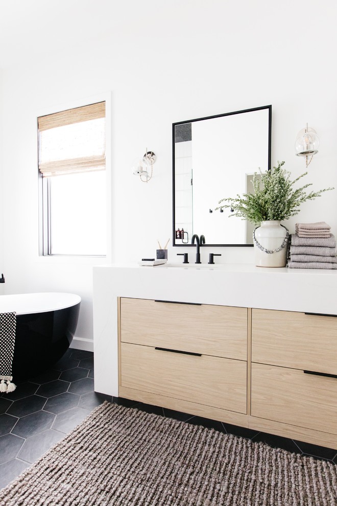 Inspiration for a medium sized scandinavian ensuite bathroom in Phoenix with flat-panel cabinets, light wood cabinets, a freestanding bath, an alcove shower, white walls, ceramic flooring, quartz worktops, black floors, a hinged door, white worktops and a submerged sink.