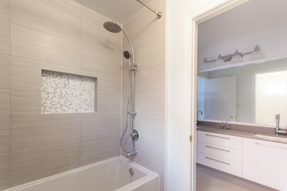 Inredning av ett modernt litet en-suite badrum, med ett undermonterad handfat, släta luckor, skåp i mellenmörkt trä, bänkskiva i kvarts, ett badkar i en alkov, grå kakel, porslinskakel, grå väggar och klinkergolv i porslin
