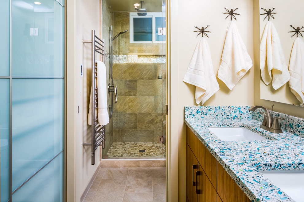 Example of a mid-sized beach style master beige tile and porcelain tile ceramic tile and beige floor alcove shower design in Other with flat-panel cabinets, medium tone wood cabinets, a wall-mount toilet, beige walls, an undermount sink, quartz countertops and a hinged shower door