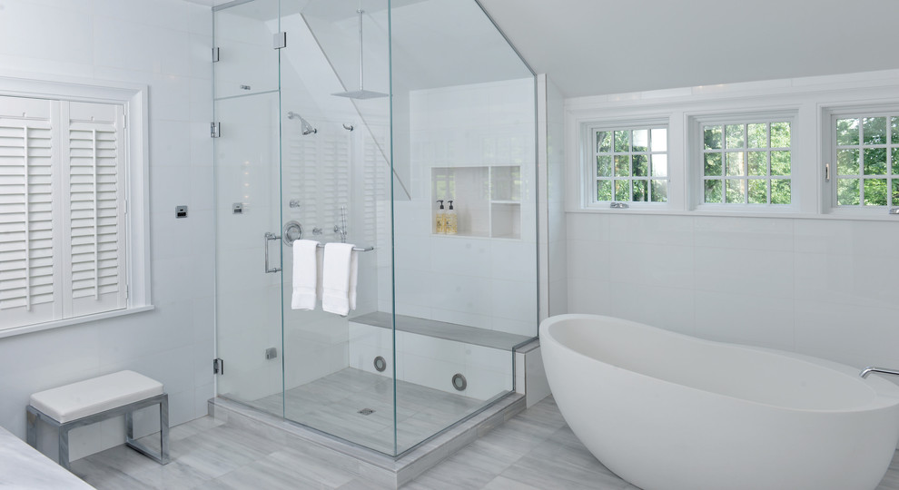 Cette image montre une grande salle de bain principale minimaliste avec une baignoire indépendante, une douche d'angle, un carrelage blanc, des carreaux de porcelaine, un mur blanc, un sol en carrelage de porcelaine, un sol gris et une cabine de douche à porte battante.